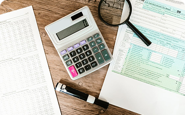 Overhead shot of a desk with a calculator, a magnifying glass, and a US Individual Income Tax Form 1040, suggesting tax preparation or audit.